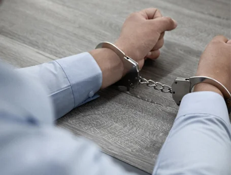 A man sitting at a desk in handcuffs