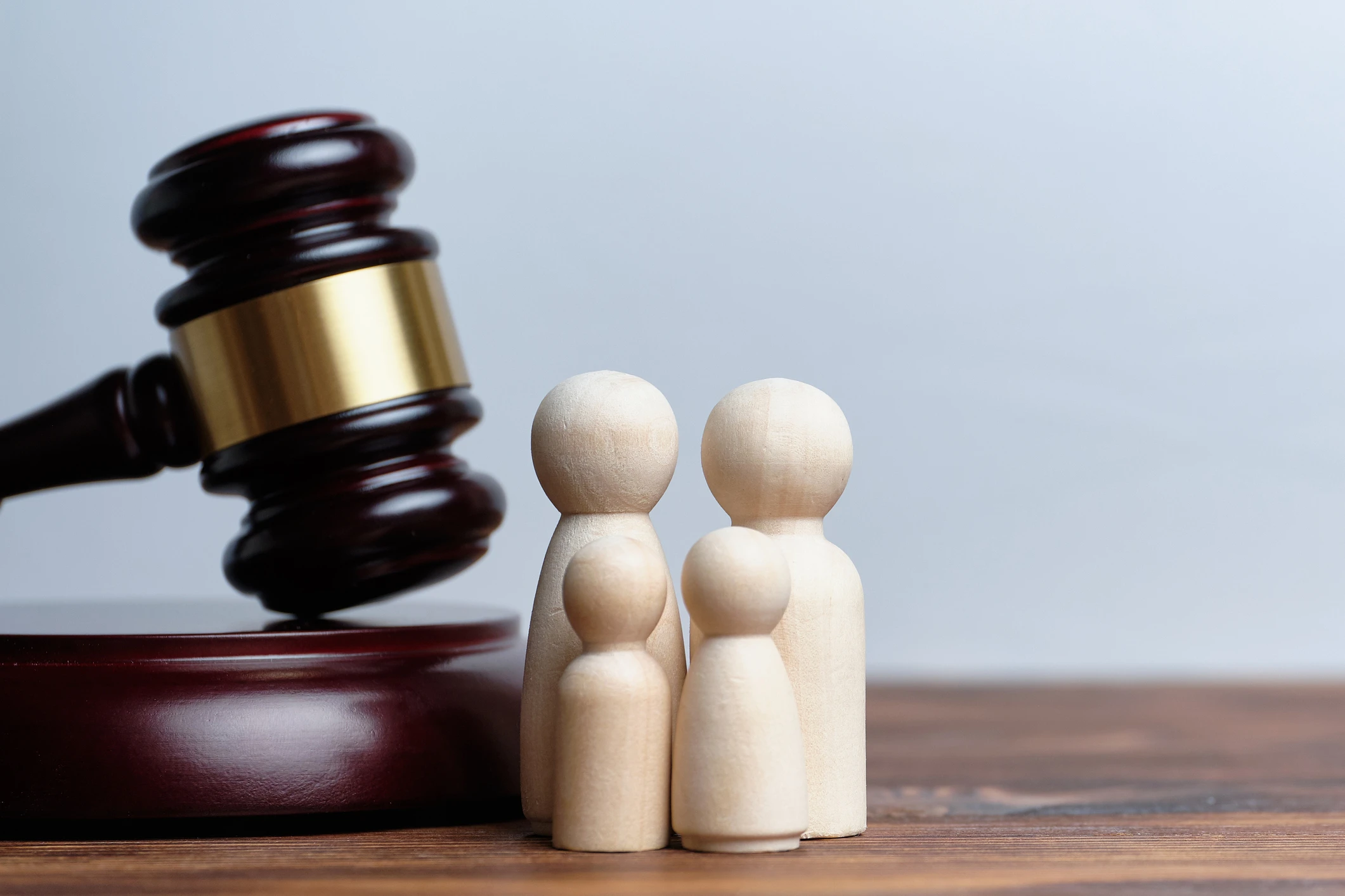 A small family of wooden figures next to a judge's gavel.