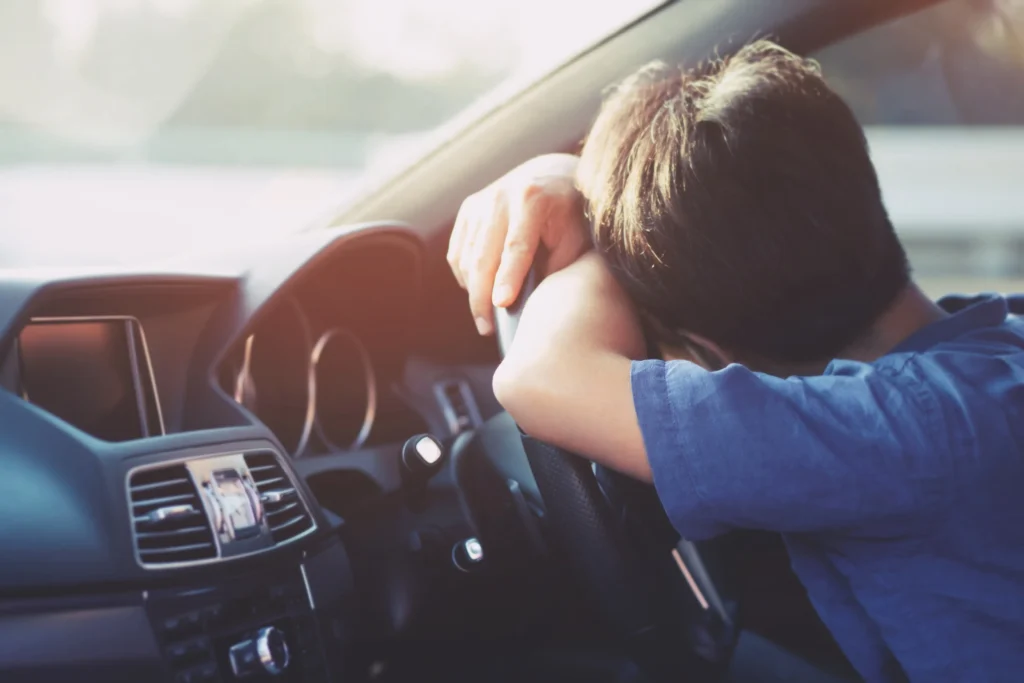 A young boy drunk and asleep on a steering wheel.