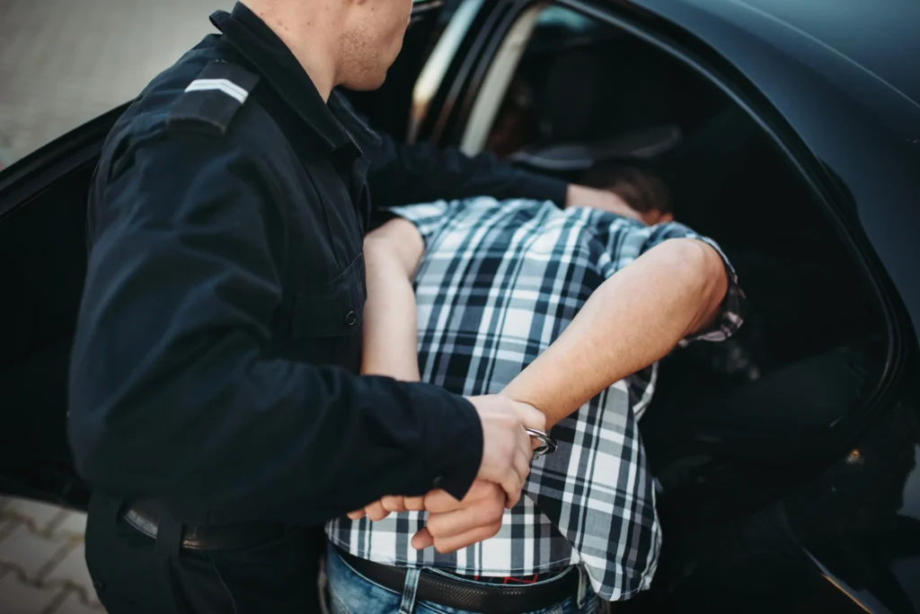 A man being arrested and put in cop car.