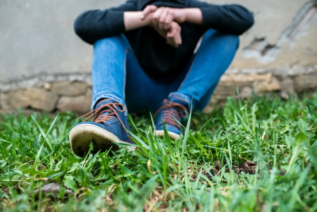 A teenager sitting in the grass.