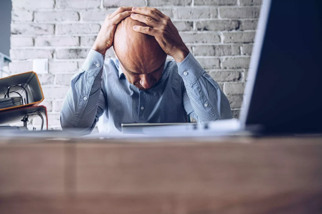 A person sitting at a table, holding his head.