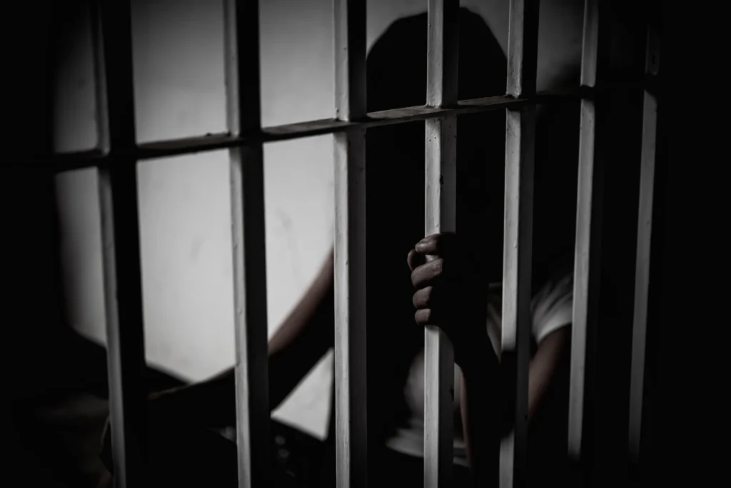 A person behind jail bars.