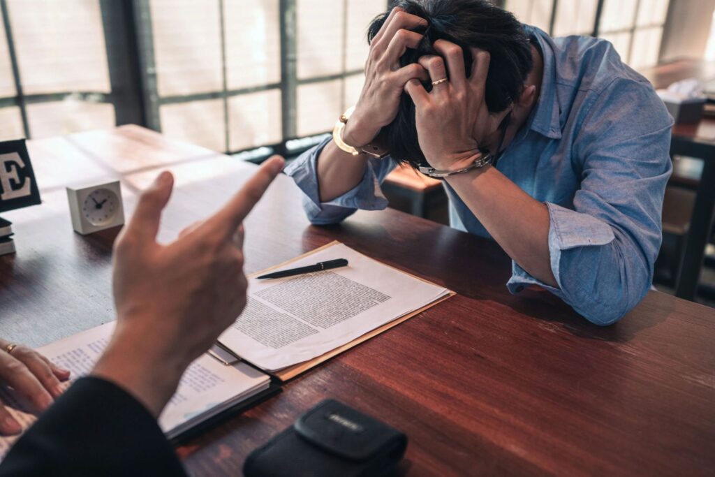 A man in handcuffs in a meeting with a lawyer.
