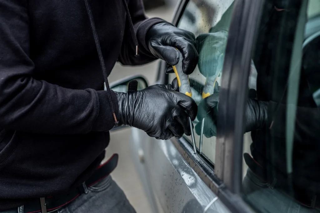 A man breaking into a car to steal items.
