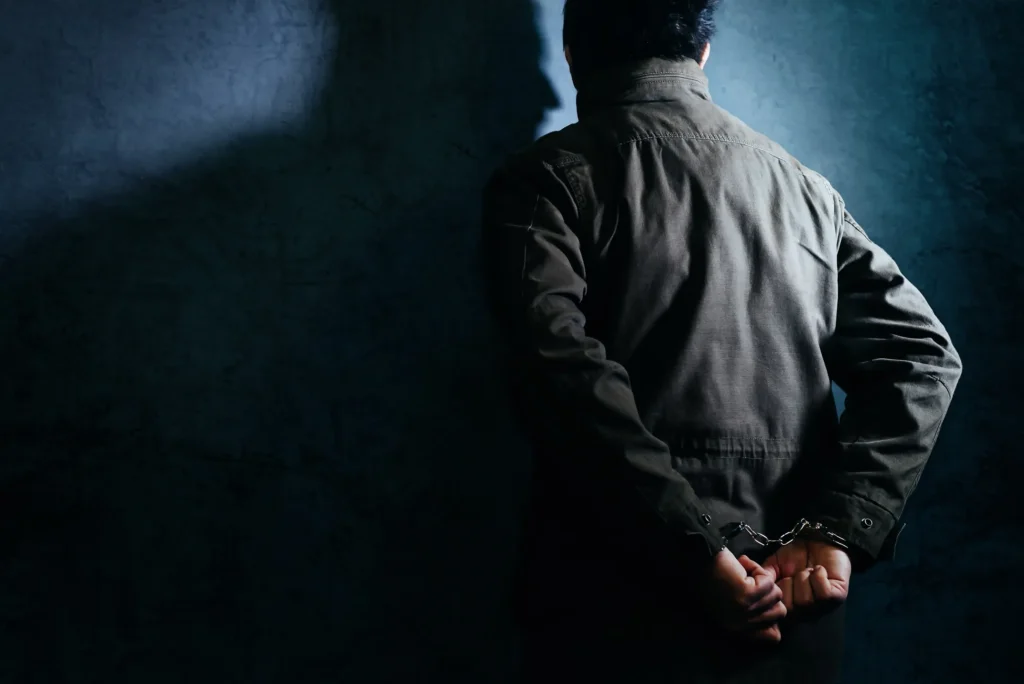 A man in handcuffs against the wall.