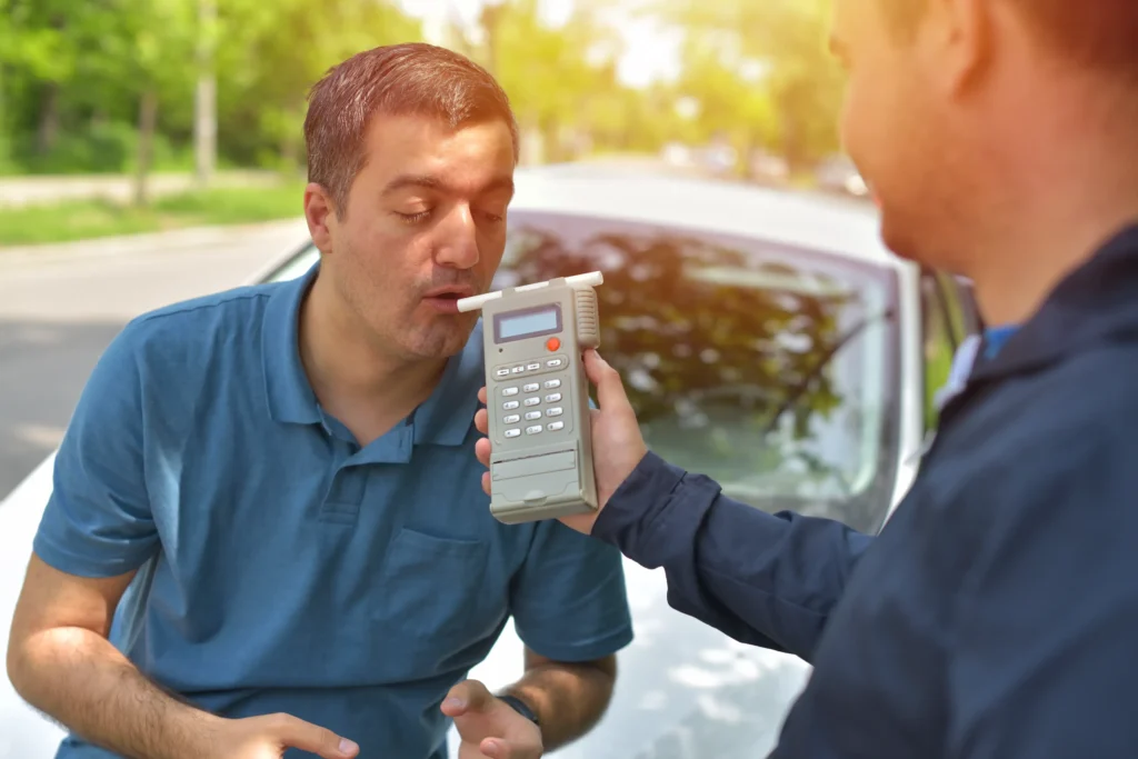 Man taking a roadside breathalyzer test from law enforcement, representing common probation violations such as drug or alcohol use in Collin County.
