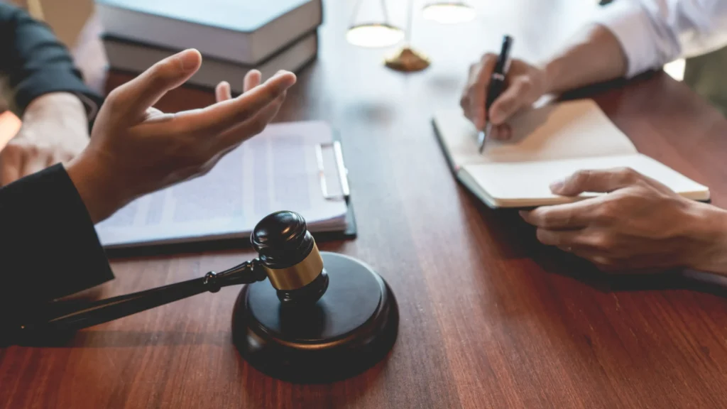 A close-up of defense attorney and client discussing legal strategy with gavel and law books on the table, illustrating potential defenses against marijuana possession in Collin County.