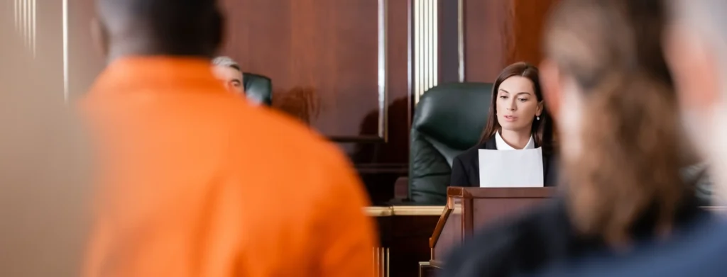 A female attorney presenting in a courtroom with a defendant in an orange jumpsuit, representing marijuana possession penalties in Collin County, Texas.