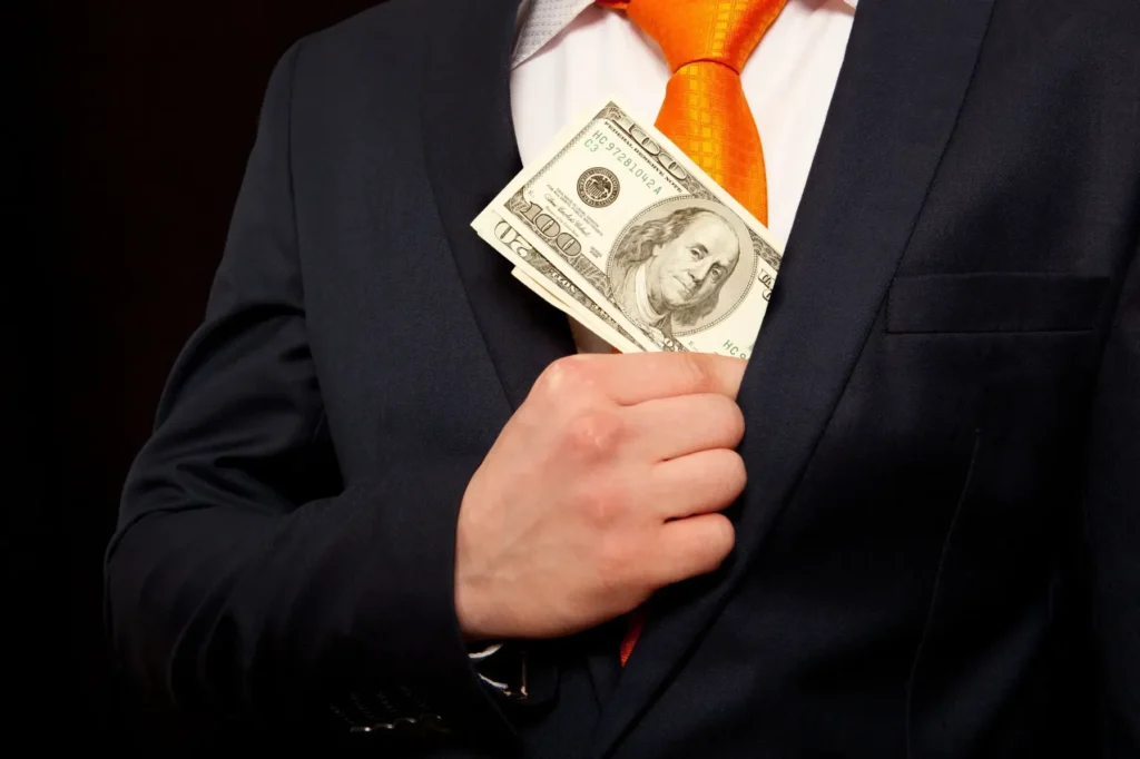 Businessperson hiding hundred-dollar bills in suit pocket, representing federal financial crimes in Dallas.