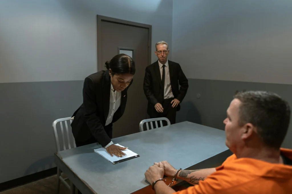 arrested person sitting at table with handcuffs being interrogated by law enforcement