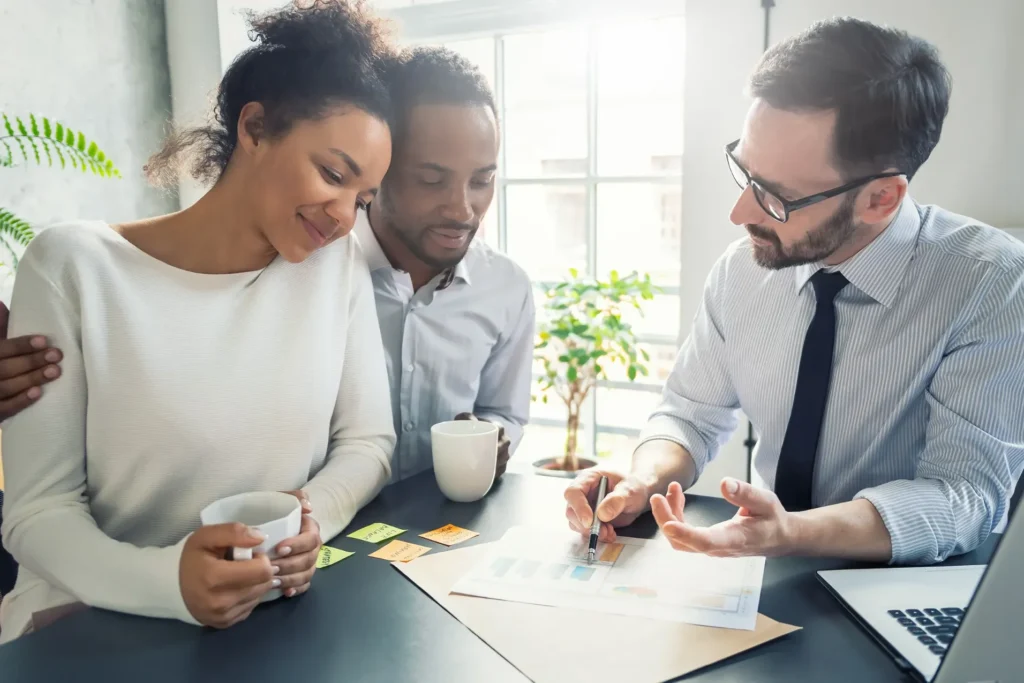 Smiling couple meeting with a professional advisor at a desk, representing supportive guidance from a Dallas family lawyer.